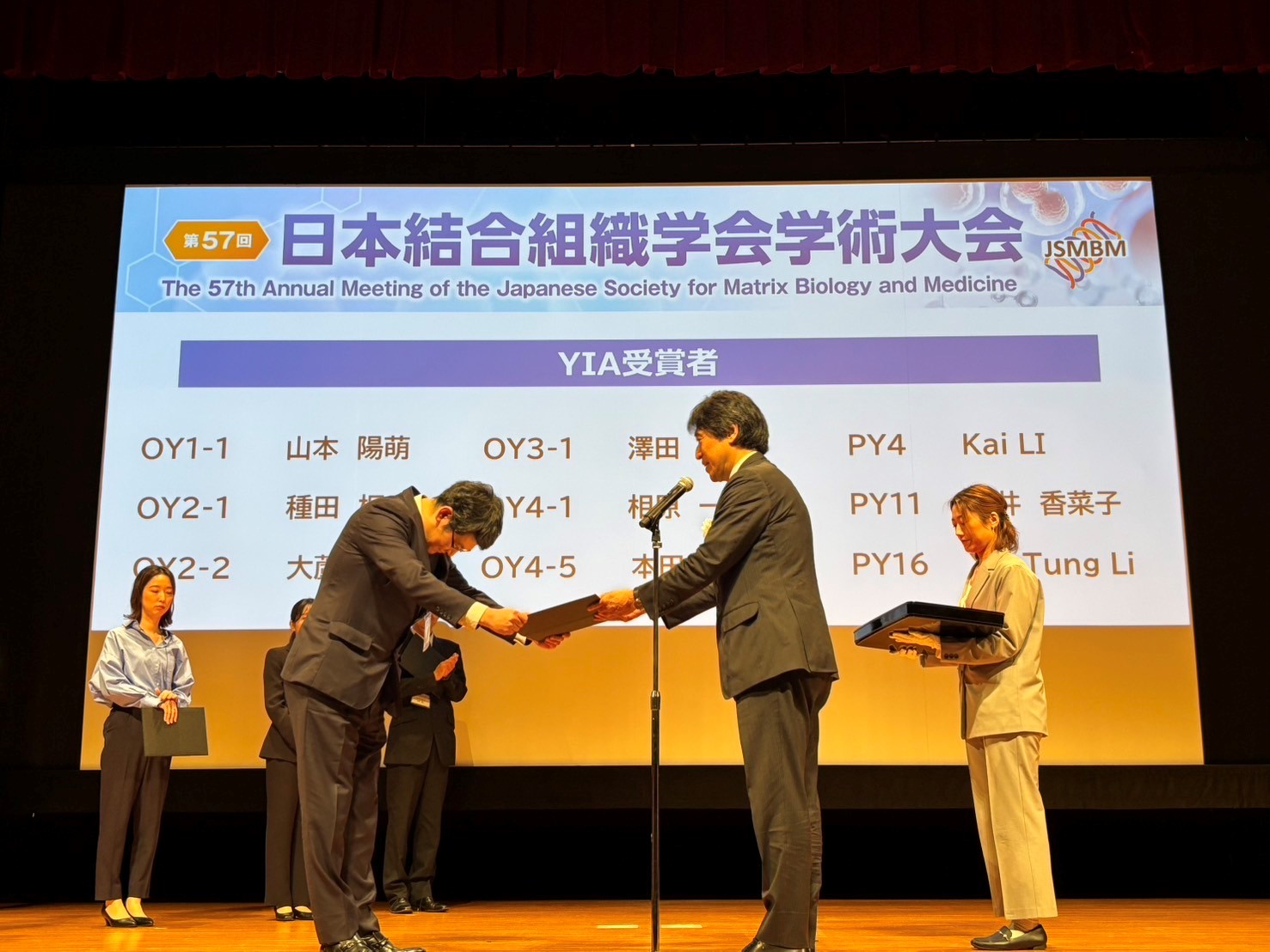玉井克人学術大会長(右)から賞状と副賞を受け取る相原一紀 研究科学生